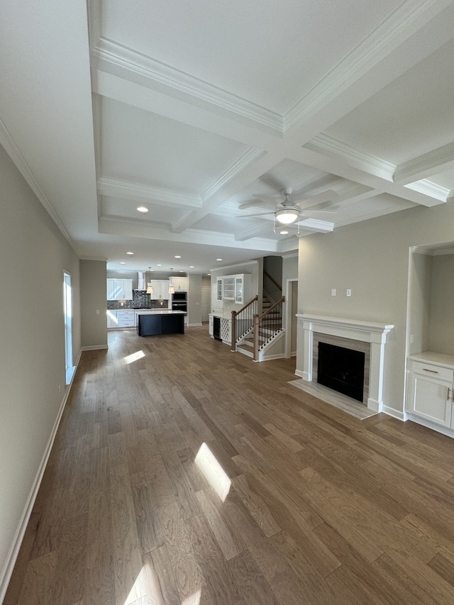 unfurnished living room with dark hardwood / wood-style floors, beamed ceiling, a fireplace, crown molding, and coffered ceiling