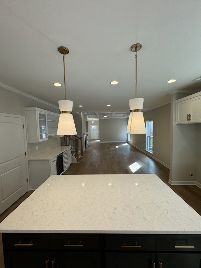 kitchen featuring a kitchen island, white cabinetry, dark hardwood / wood-style floors, crown molding, and decorative light fixtures