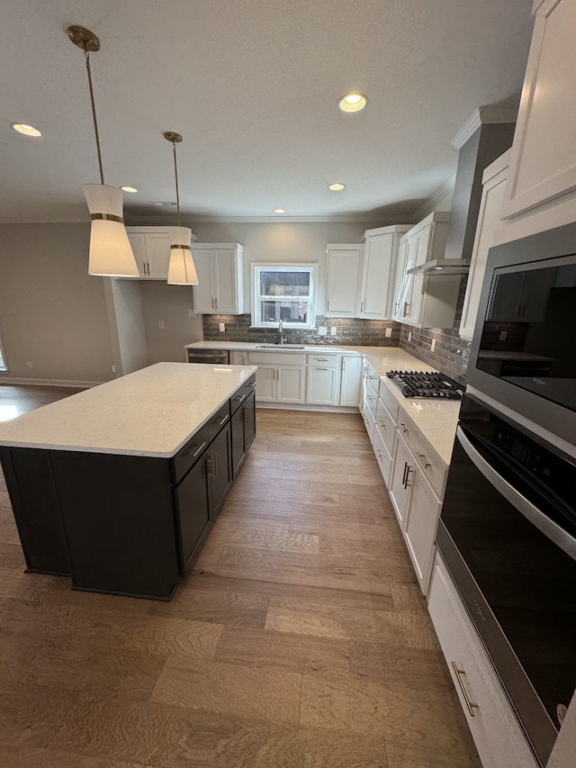 kitchen featuring a kitchen island, white cabinetry, stainless steel appliances, sink, and decorative light fixtures