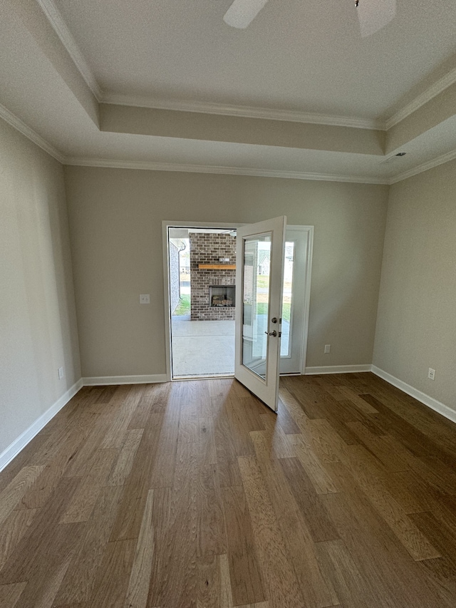 empty room with ornamental molding, hardwood / wood-style floors, a brick fireplace, and a textured ceiling