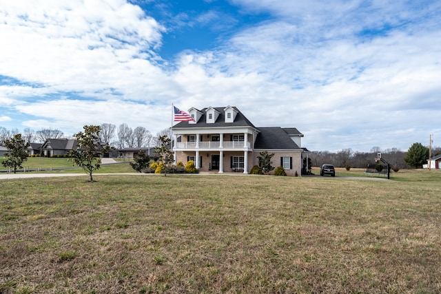 view of front of house with a balcony and a front lawn