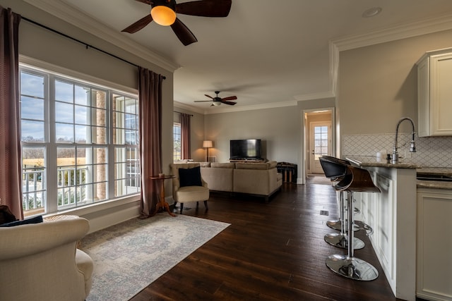 living room featuring dark hardwood / wood-style floors, ceiling fan, crown molding, and a wealth of natural light