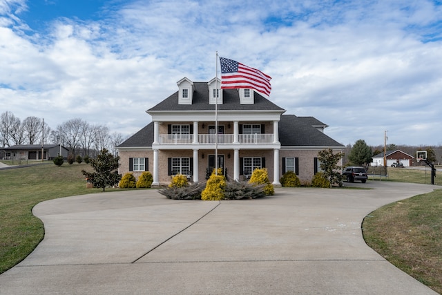 view of front of home featuring a balcony, covered porch, and a front lawn