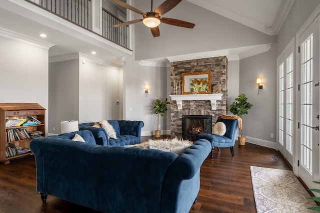 living room featuring a fireplace, a high ceiling, ceiling fan, ornamental molding, and dark wood-type flooring