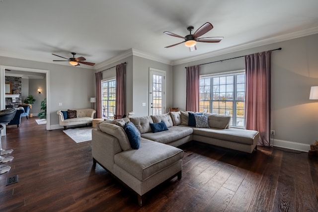 living room featuring dark hardwood / wood-style flooring, ceiling fan, crown molding, and a stone fireplace