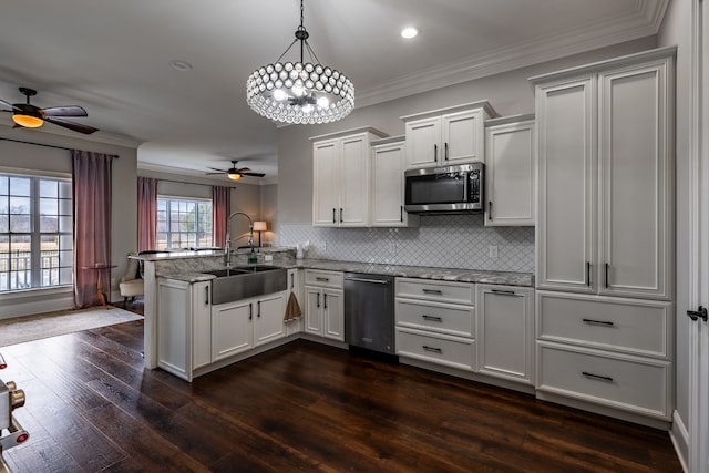 kitchen with sink, stainless steel appliances, kitchen peninsula, and ceiling fan with notable chandelier