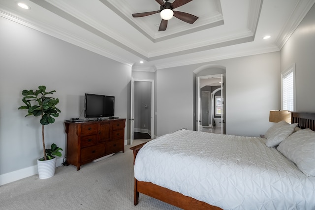 carpeted bedroom featuring ceiling fan, crown molding, a tray ceiling, and connected bathroom