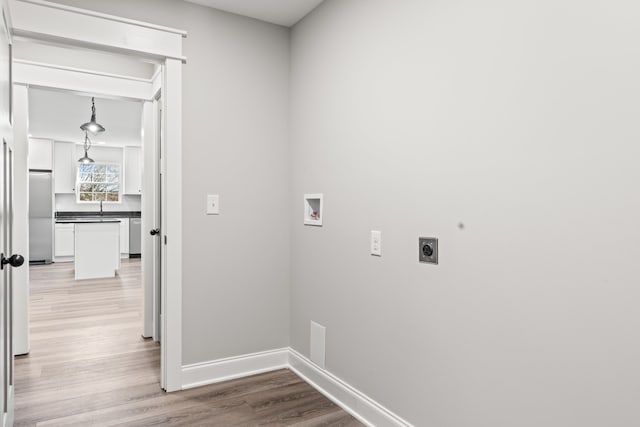 clothes washing area featuring washer hookup, light hardwood / wood-style floors, and hookup for an electric dryer