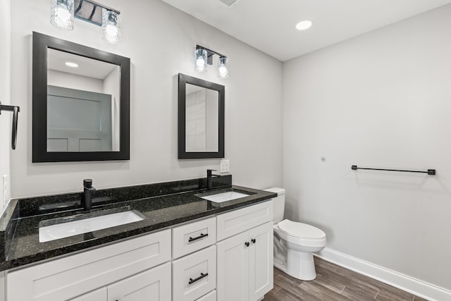 bathroom featuring hardwood / wood-style floors, toilet, double sink, and vanity with extensive cabinet space