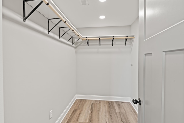 walk in closet with light hardwood / wood-style flooring