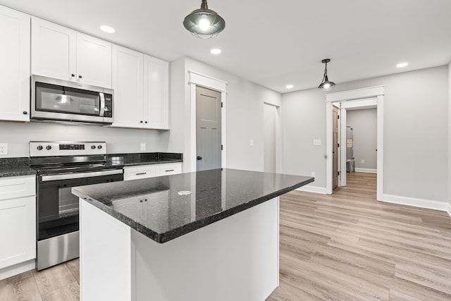 kitchen with appliances with stainless steel finishes, pendant lighting, light wood-type flooring, and white cabinets