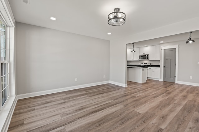 unfurnished living room featuring light hardwood / wood-style floors and an inviting chandelier