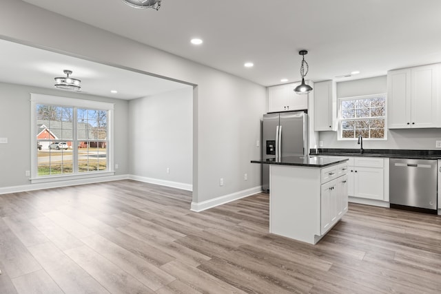 kitchen featuring decorative light fixtures, light hardwood / wood-style flooring, white cabinetry, and stainless steel appliances