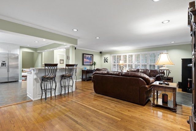 living room with light wood-type flooring, ornamental molding, and indoor bar