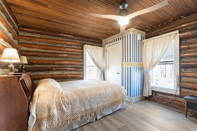 bedroom with hardwood / wood-style flooring, log walls, ceiling fan, and wooden ceiling