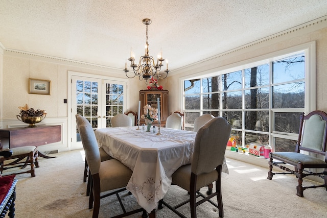 carpeted dining room featuring a notable chandelier and a textured ceiling