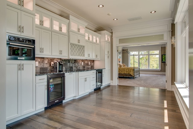 kitchen featuring beverage cooler, dark stone counters, backsplash, and white cabinets