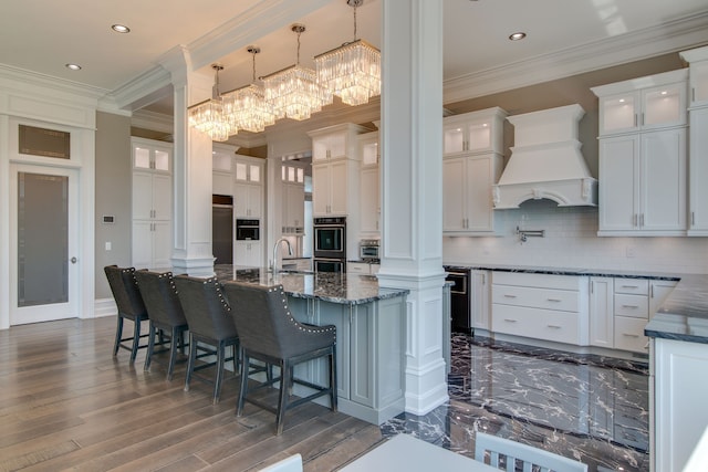 kitchen with backsplash, an inviting chandelier, a kitchen breakfast bar, custom range hood, and pendant lighting