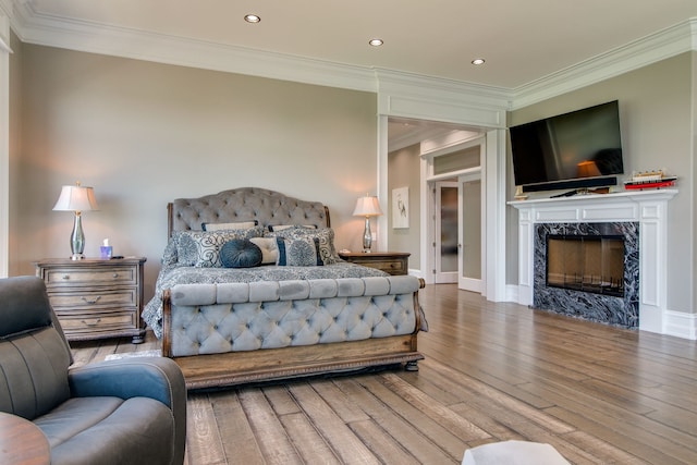 bedroom featuring ornamental molding, a premium fireplace, and wood-type flooring