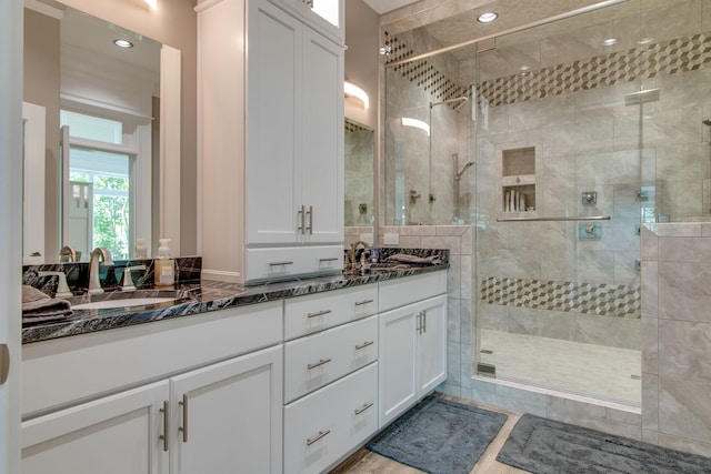 bathroom with tile walls, a shower with door, and double vanity