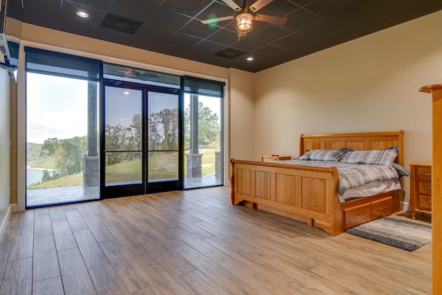 bedroom with ceiling fan, access to exterior, a drop ceiling, and light hardwood / wood-style floors