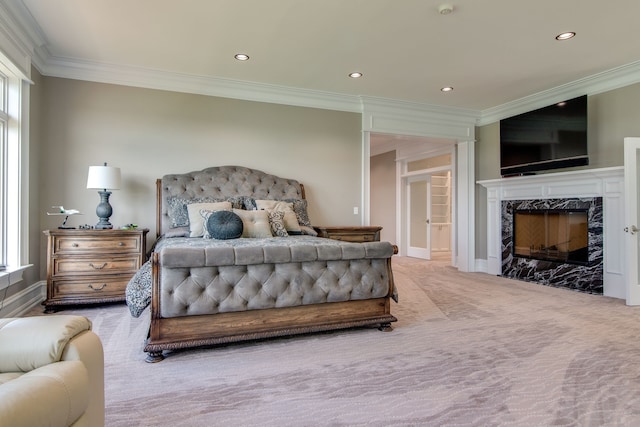 bedroom with a high end fireplace, crown molding, and light carpet