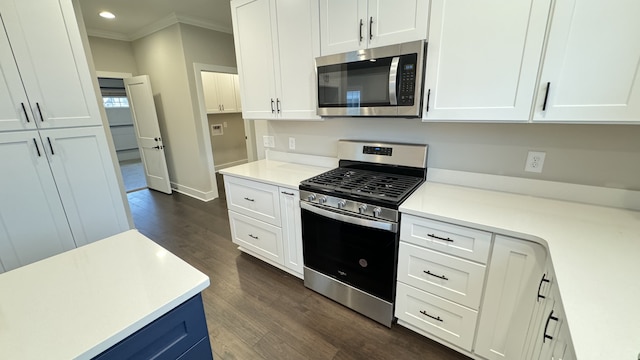 kitchen featuring white cabinets, dark wood-type flooring, appliances with stainless steel finishes, and crown molding