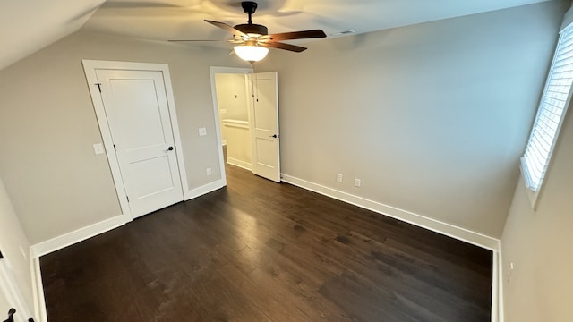 unfurnished bedroom with ceiling fan, dark wood-type flooring, and multiple windows