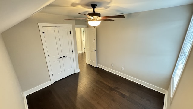 unfurnished bedroom featuring ceiling fan, lofted ceiling, dark wood-type flooring, and a closet