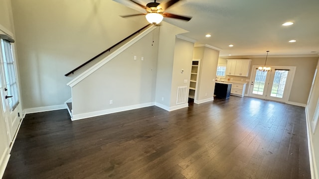 unfurnished living room featuring ornamental molding, dark wood-type flooring, and ceiling fan with notable chandelier