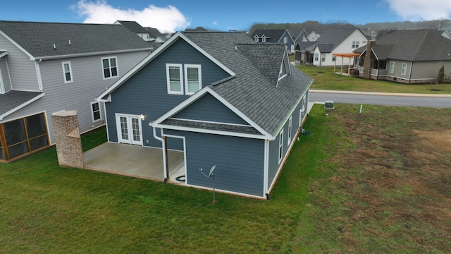 rear view of house featuring french doors, a lawn, and a patio area