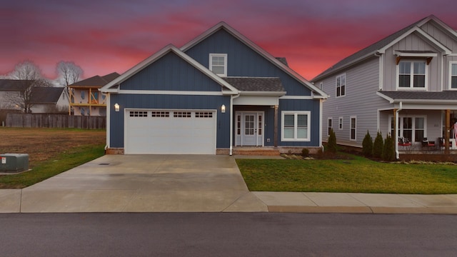 craftsman-style house featuring a porch, a yard, central AC unit, and a garage