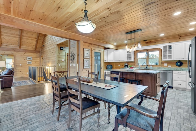 dining space featuring lofted ceiling, wooden walls, and wood ceiling