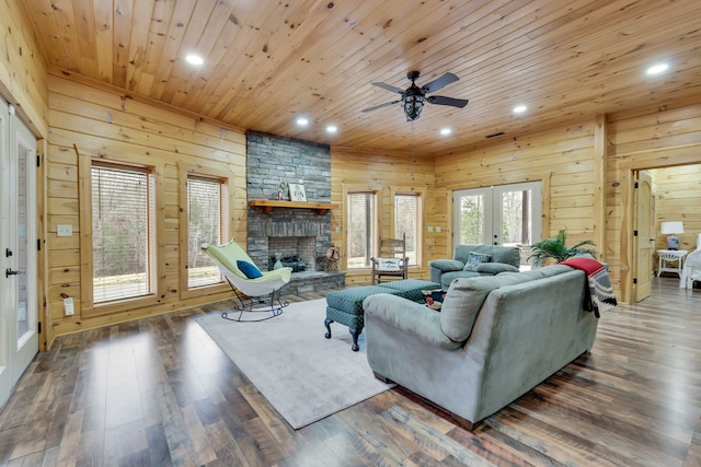 living room with ceiling fan, a fireplace, wood walls, and dark wood-type flooring