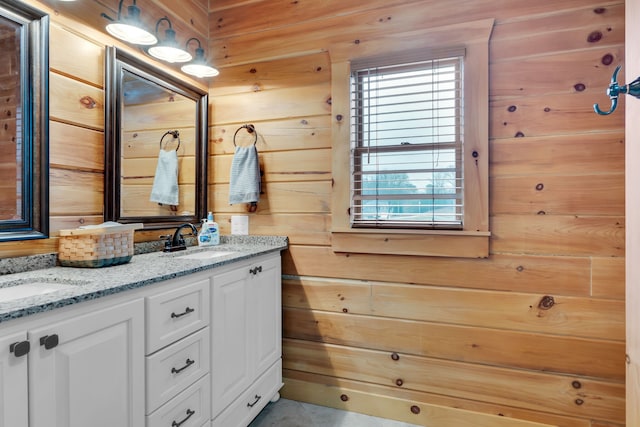 bathroom with wood walls, dual vanity, and a wealth of natural light