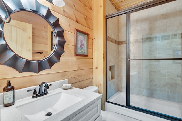 full bathroom featuring vanity, wooden walls, shower / bath combination with glass door, and toilet