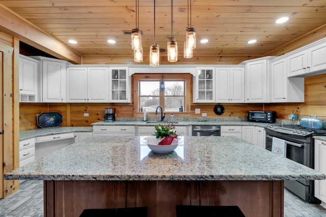 kitchen featuring hanging light fixtures, a center island, a breakfast bar, stove, and white cabinets