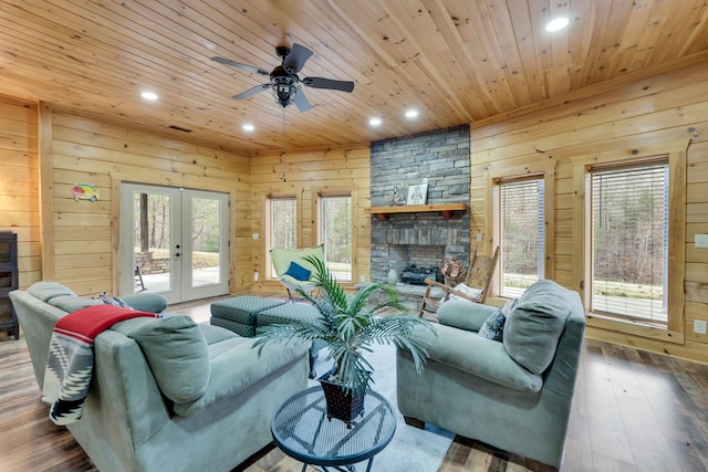 living room featuring dark hardwood / wood-style flooring, ceiling fan, wood walls, and a fireplace