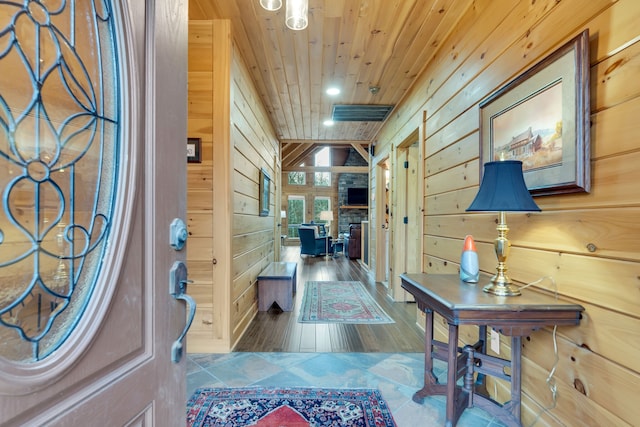 entrance foyer featuring a stone fireplace, wooden walls, hardwood / wood-style floors, and wood ceiling