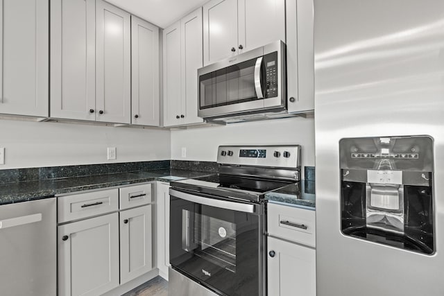 kitchen with white cabinetry, appliances with stainless steel finishes, and dark stone countertops