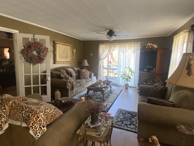 living room featuring wood-type flooring, ceiling fan, and crown molding