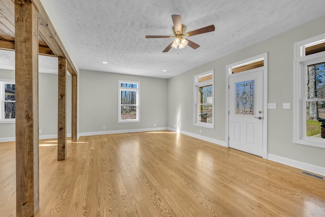 interior space with a textured ceiling, ceiling fan, a healthy amount of sunlight, and light wood-type flooring