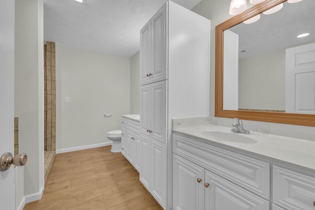 bathroom featuring vanity, a textured ceiling, hardwood / wood-style floors, and toilet