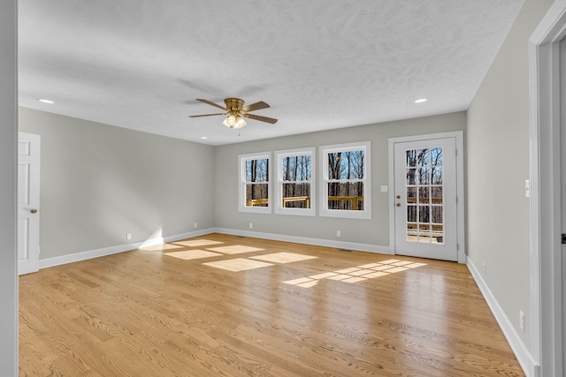 empty room with ceiling fan, a textured ceiling, and light wood-type flooring