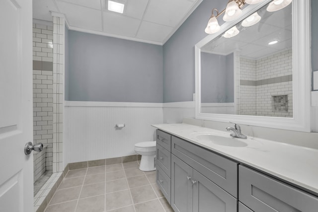 bathroom with tile flooring, a paneled ceiling, toilet, and oversized vanity