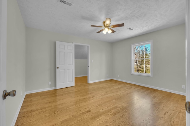 spare room with ceiling fan, a textured ceiling, and light wood-type flooring