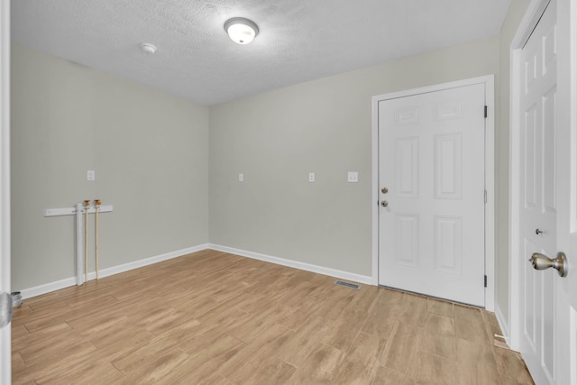 unfurnished room with light wood-type flooring and a textured ceiling