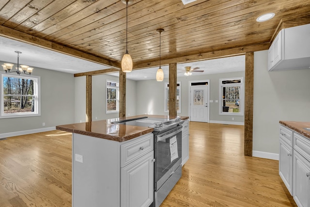 kitchen with stainless steel range with electric stovetop, light hardwood / wood-style flooring, decorative light fixtures, ceiling fan with notable chandelier, and white cabinetry