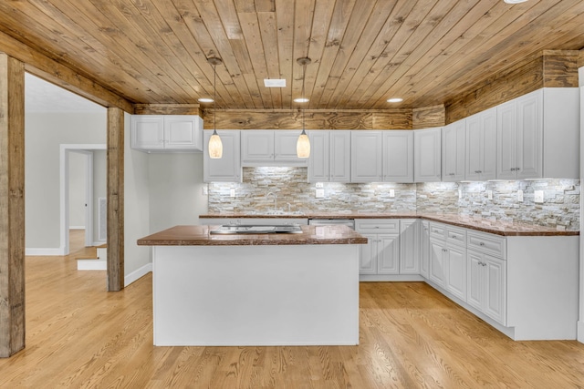 kitchen featuring hanging light fixtures, a kitchen island, backsplash, light hardwood / wood-style floors, and white cabinetry