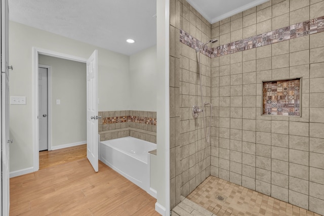 bathroom featuring plus walk in shower, ornamental molding, and hardwood / wood-style flooring